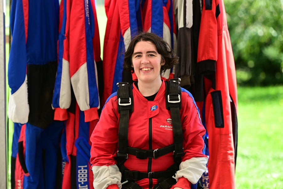 Myriam porte une combinaison rouge, et se prépare pour un saut en parachute.